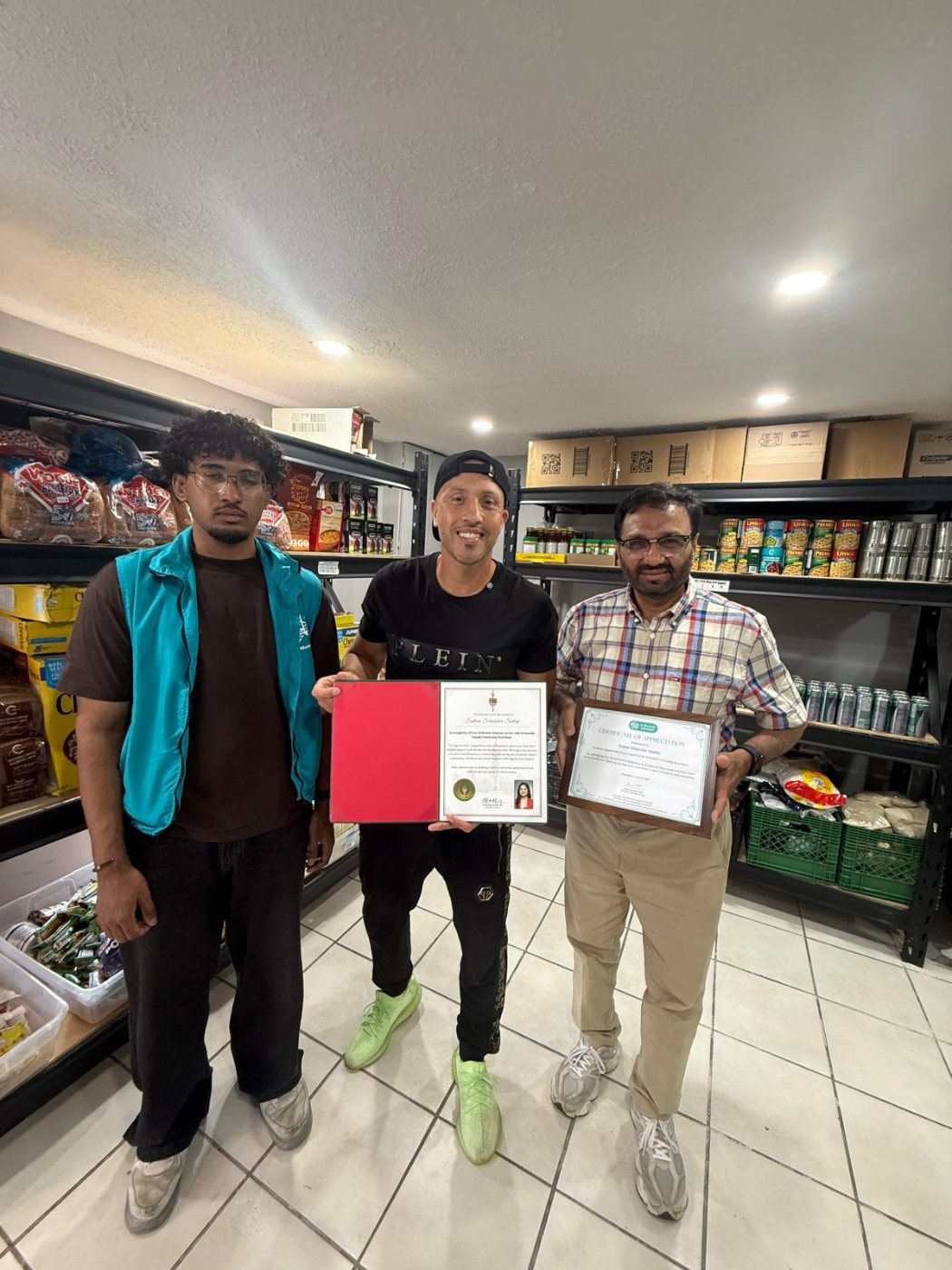Three volunteers holding certificates of appreciation at a local food bank