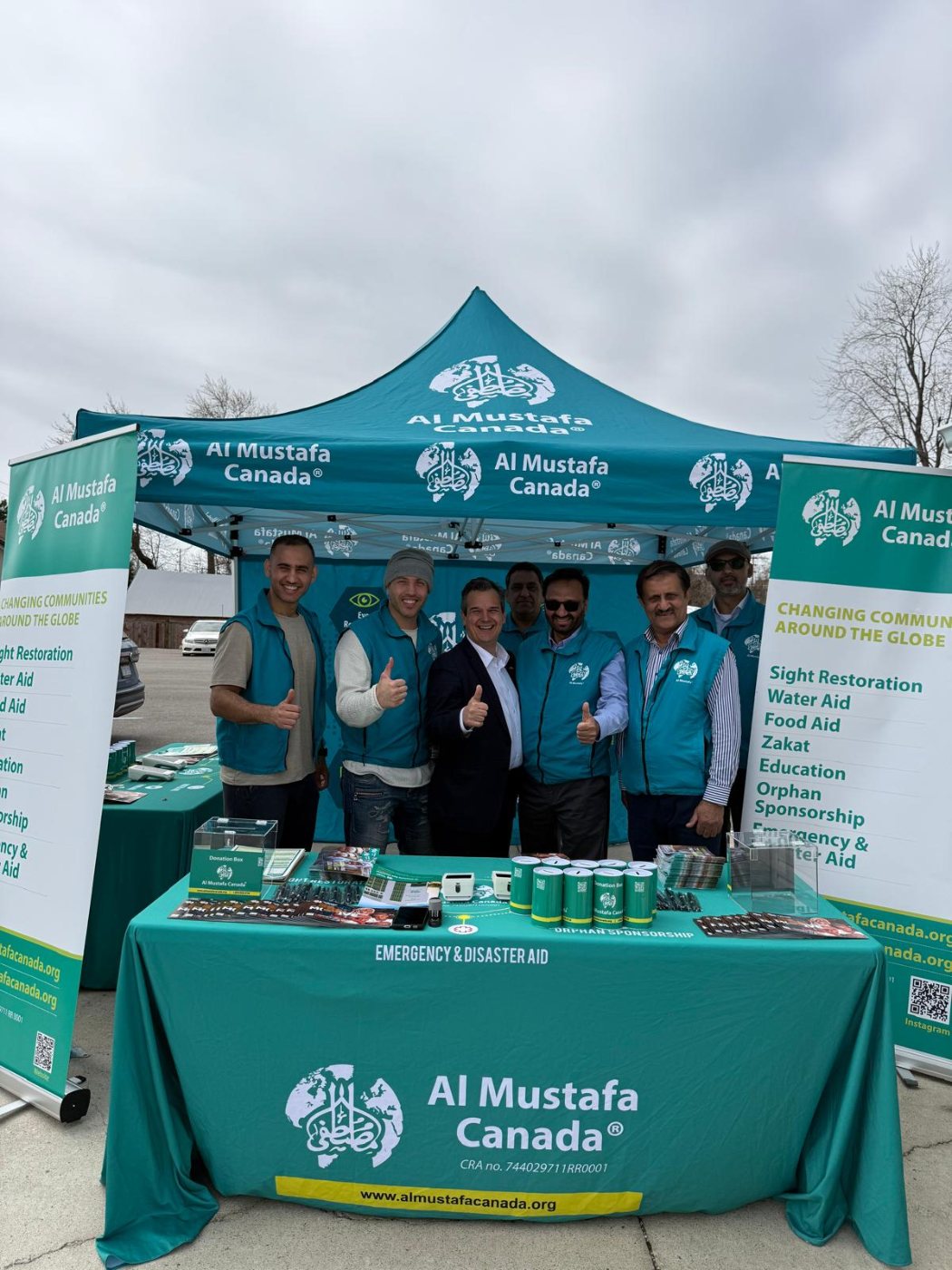 Volunteers standing behind a community outreach stand at an outdoor event