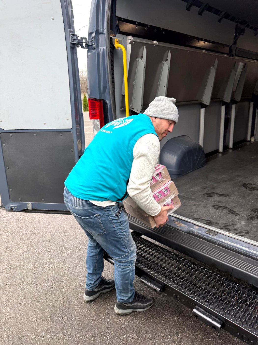 A volunteer unloading boxes of food donations from a delivery truck